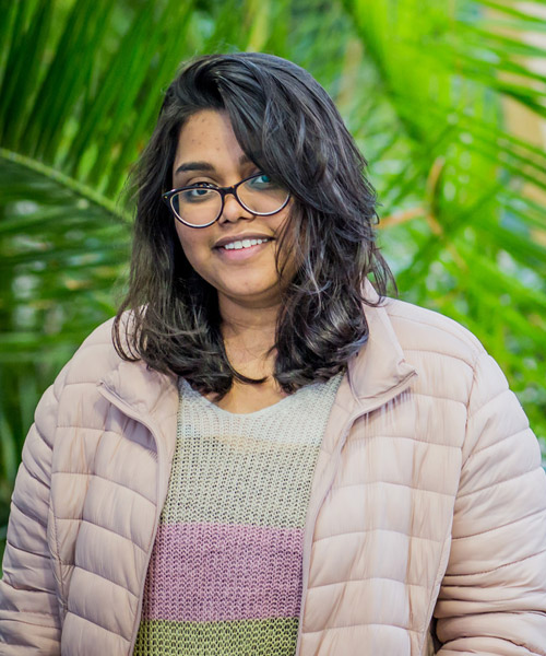 Headshot of Sravani Karnam in front of some greenery.