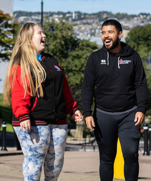 Three students laughing and walking towards the camera.