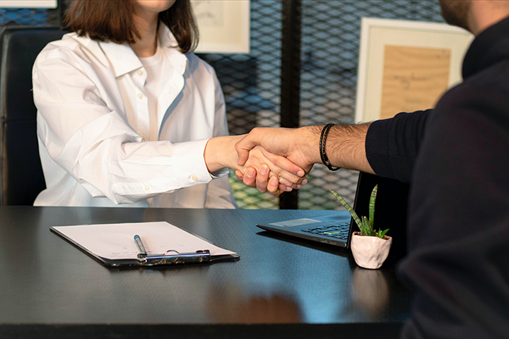 Two people shaking hands at a desk