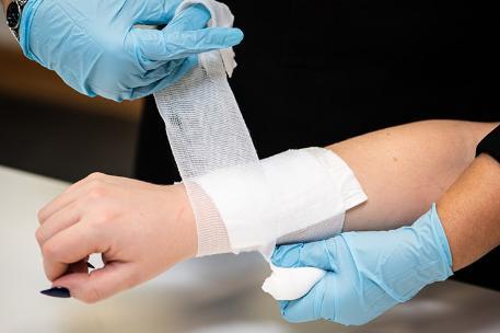 Someone having their arm bandaged by a First-Aider