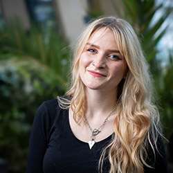 Molly, Public Health and Community Wellbeing student, posing in a foliage decorated room in Bright Building.