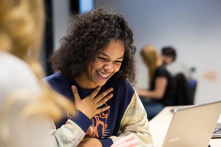 Student smiling at their laptop.