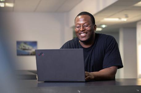 Student sitting behind their laptop and smiling.