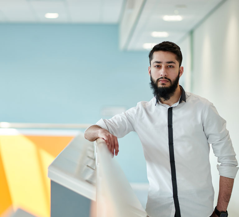 A student with an arm on a railing looking at the camera