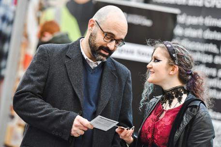 A student and a parent or carer smiling and looking at a brochure