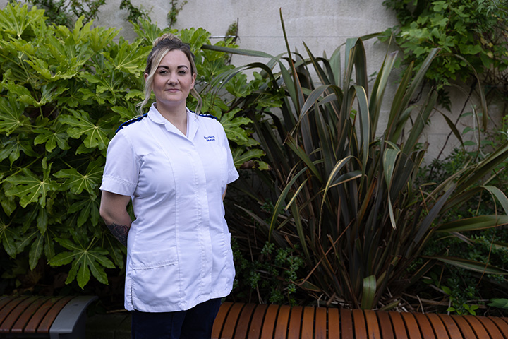 A student dressed in a nurses uniform smiles at the camera