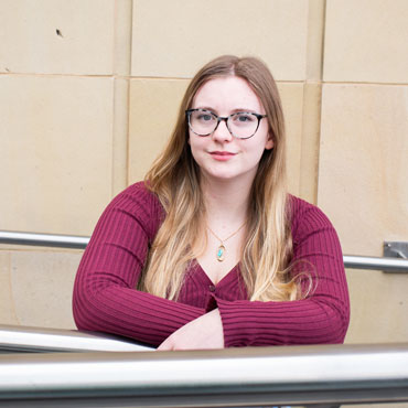 A student leaning on a railing in the Richmond Atrium at University of Bradford