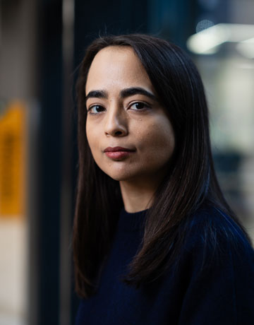 A person looking at the camera while standing in the Richmond Atrium at the University of Bradford