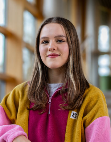 A student smiling at the camera on campus at Bradford