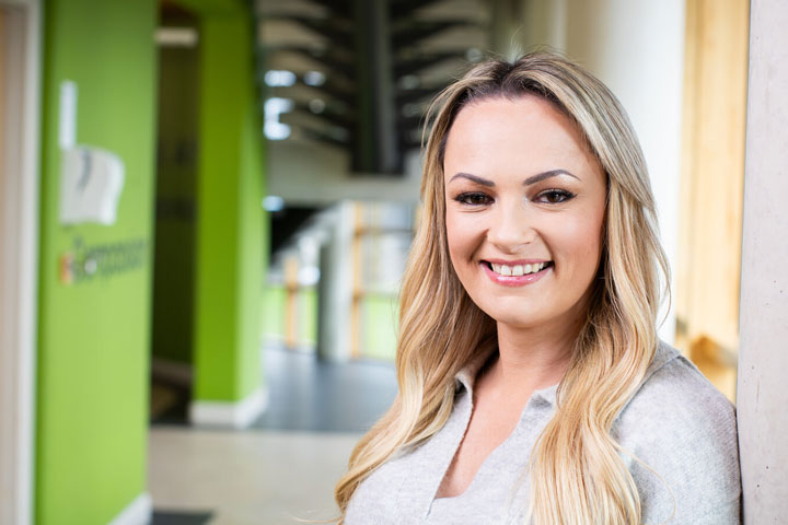 A student smiling at the camera and standing in a corridor