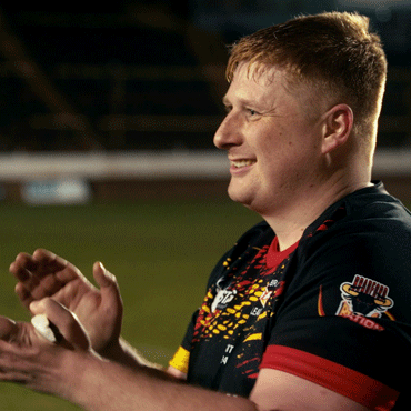 A student on the rugby pitch looking to the left with hands ready to catch a ball