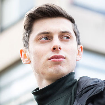 A student standing in front of a building looking into the distance