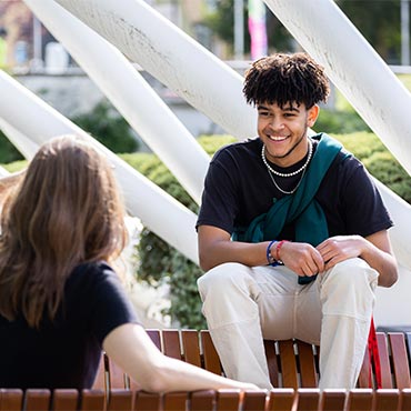 Two students sitting outside and chatting.