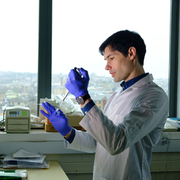 A researcher using a pipette in a research lab, they are in a state-of-the-art research lab overlooking the city skyline.