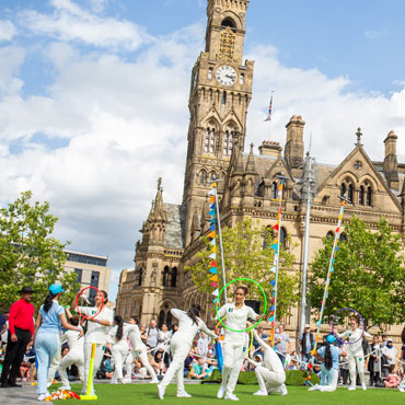 A group of people dressed in white performing in front of Bradford city hall