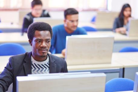 A male student sat at a computer in a class