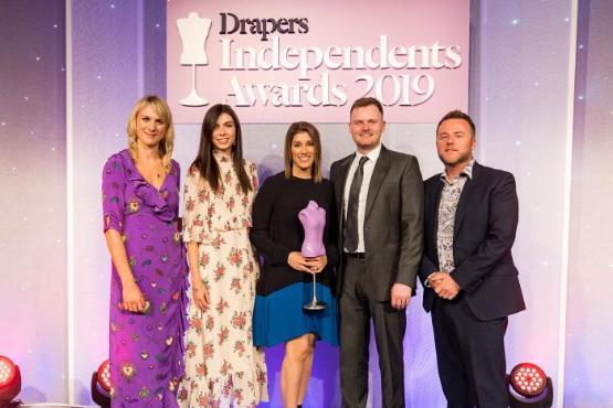 Sonya Bachra-Byrne (MBA, 2023) standing on stage with her team after receiving the Drapers Independents Fashion Award for her fashion business AVIE.