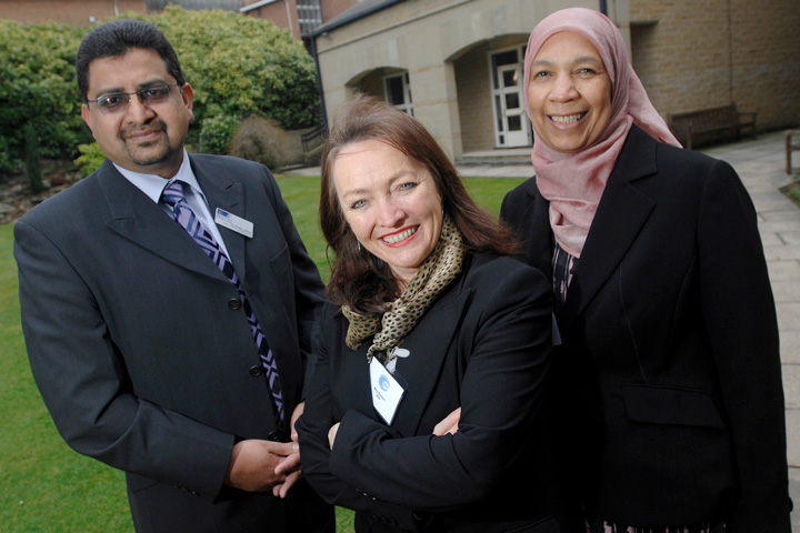 Three individuals smiling whilst taking a picture 