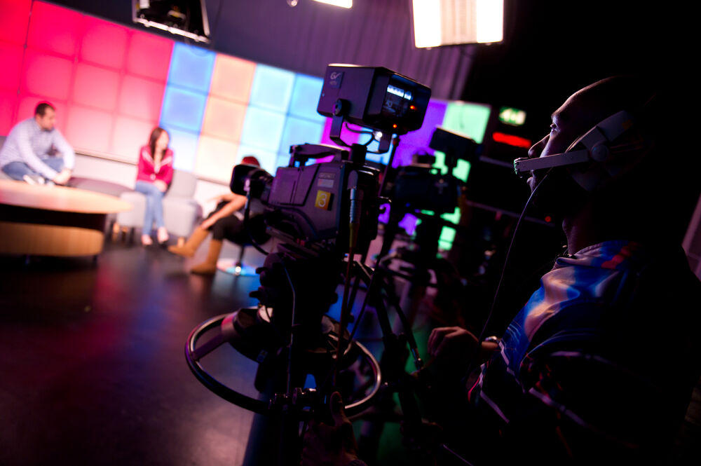 A person operating a camera in a TV studio