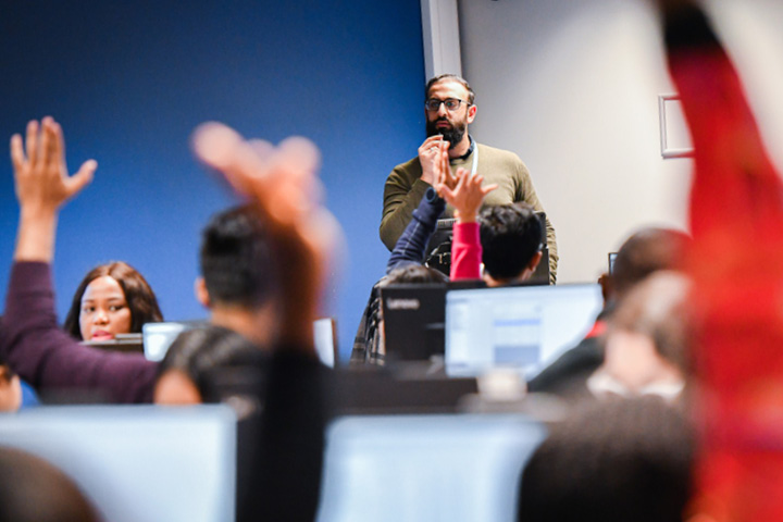 Students in class raising their hands to ask a question.