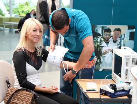 A woman sitting with a cuff around her arm to measure blood pressure and heart rate