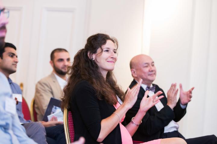 Audience members at an alumni event smiling and clapping