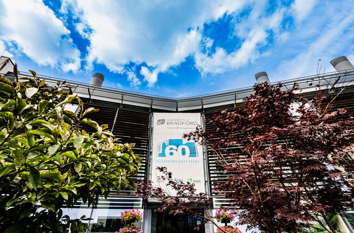 Photo of School of Management with 60th Anniversary banner behind landscape in 2023