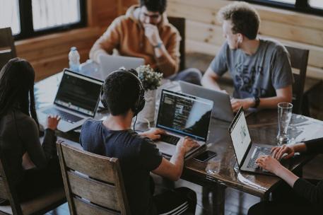 Students at a group project meeting working on laptops