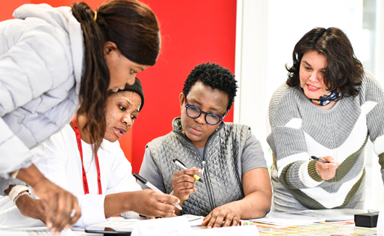 A group of students with pens in their hands working together.