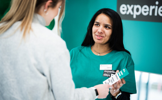 Student ambassador handing a brochure to a visitor at an Open Event.