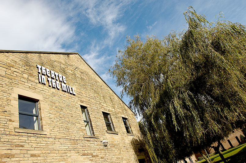 Exterior of the Theatre In The Mill building and trees on a bright sunny day.