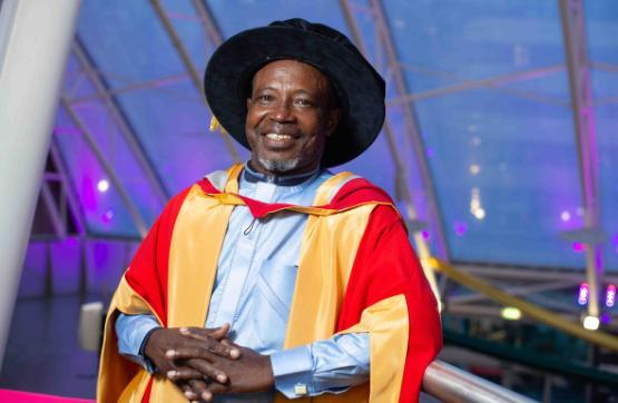 Honorary graduate in cap and gown smiles for camera