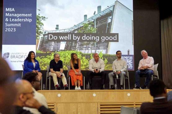 Staff sat down on chairs on a stage at summit event