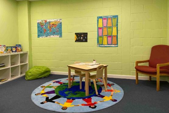 A room with a small wooden table and two posters on the wall and a rug on the floor