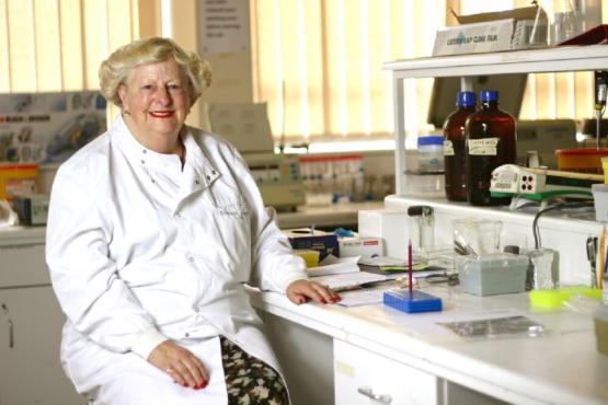 An academic wearing a white coat sitting down inside a laboratory