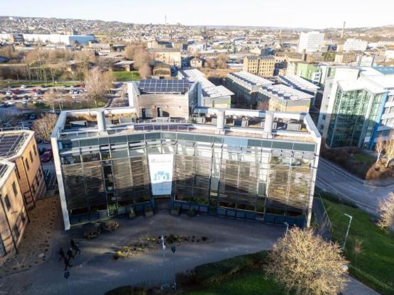 A drone image of the University of Bradford's School of Management building which also features buildings in Bradford behind it