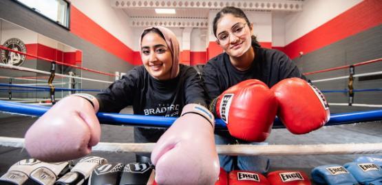 Students Dr Alaa Alshaabi and Nimra Hassan wearing boxing gloves in the ring