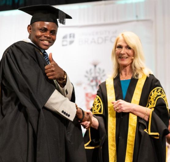 Professor Shirley Congdon shakes the hand of a graduate on stage