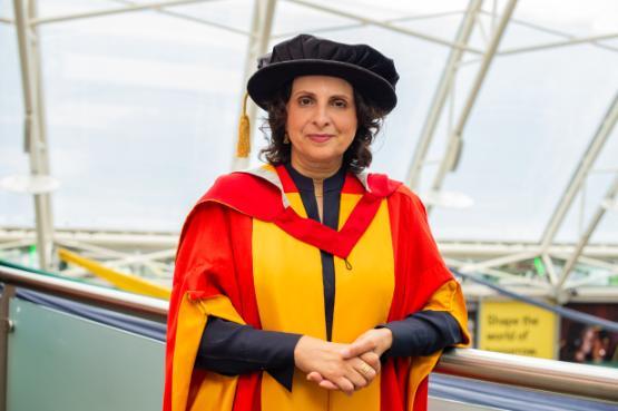 A woman sanding wearing graduation robes