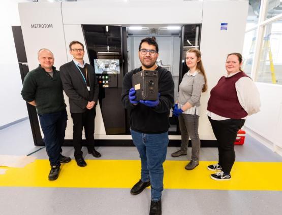 Academics holding original Cottingley Fairy camera in front of a CT scanner