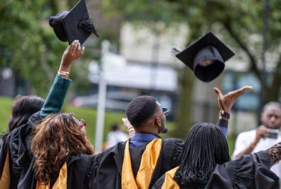 Graduates throwing mortar boards in air