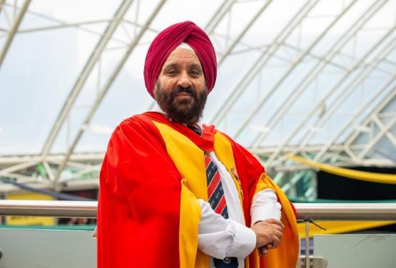 Honorary graduate dressed in gown stands for photograph