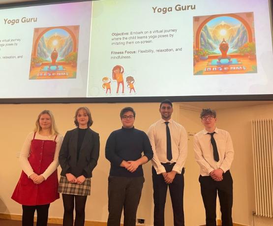 Five students stand up in front of projector screen showing a cartoon graphic above their heads