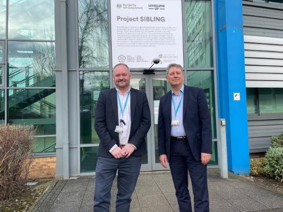 Two staff members stood outside entrance to university building