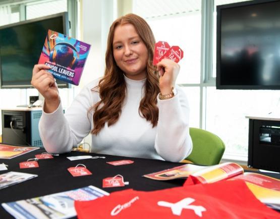 a person sat at a table holding up a brochure in each hand