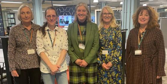 Five members of staff stand next to each other in a new library building at the university