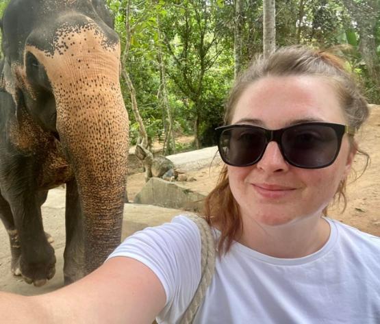 A student standing in front of an elephant