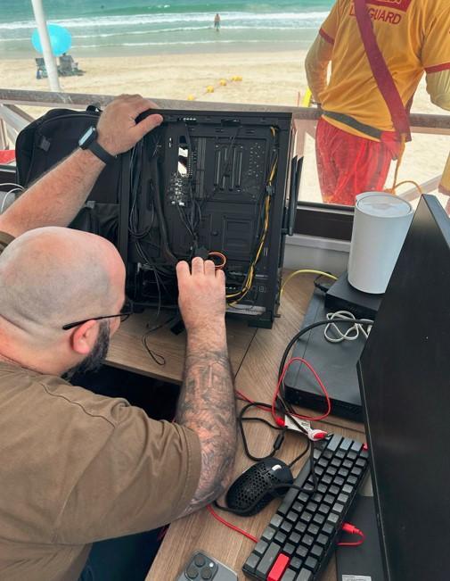 Karl Baz setting up a computer by the beach