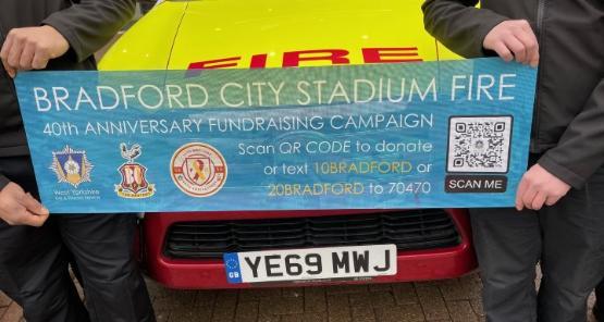 A close up photograph of a charity appeal being held against a marked fire service vehicle