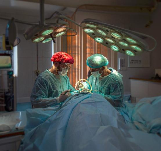 Two surgeons wearing medical gowns operating on a patient